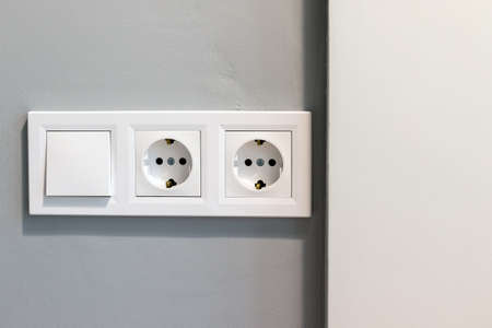 Group of white european electrical outlets and a switch located on a gray wall. Closeup viewの写真素材