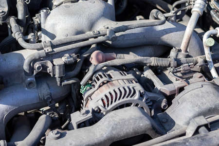 Dusty details of a flat-four (boxer) car engine compartment under the open hood. Alternator and intake manifoldの写真素材