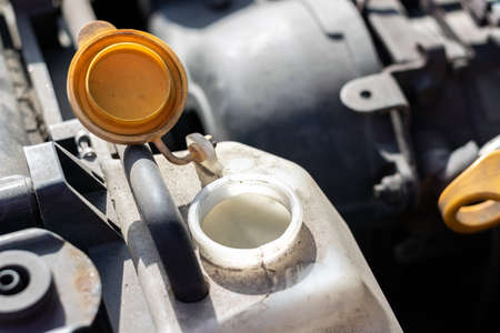 Open lid on an antifreeze tank. Dusty details of a flat-four (boxer) car engine compartment under the open hood. Closeup view on a sunny dayの写真素材