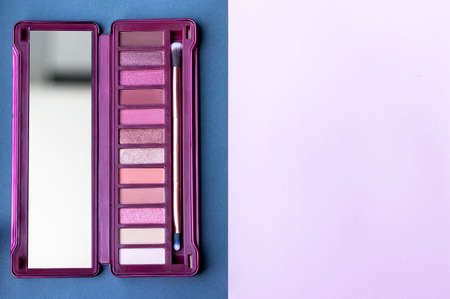 Colorful eye shadow palette in pink colors on gray, pink, lilac paper background with copy space. Professional color palette with brush for day and evening eye makeup with matte and shimmer shadowsの写真素材