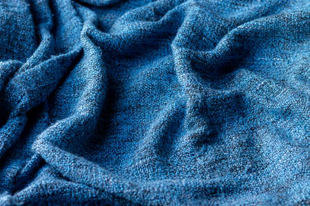 Bright blue knitted fabric texture. Crumpled blanket background. Selective focus. Closeup view