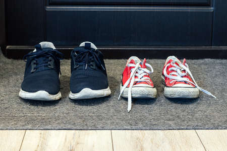 Family blue shoes and red sneakers on the rug at the front door. Closeup viewの写真素材