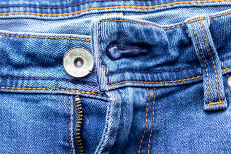 Jeans front with zipper open, button and pockets. Bright blue denim fabric texture background. Closeup view. Selective focusの写真素材