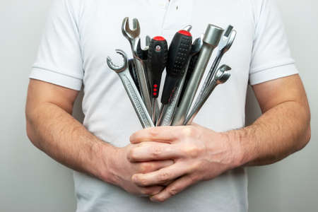A man in a white T-shirt with a bouquet of wrenches and screwdriversの写真素材