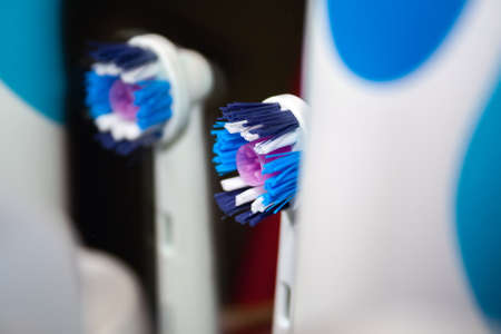 Closeup view of the used blue and white brush head for an electric toothbrush with a pink rubber centerpiece for the best distribution of toothpaste. The toothbrush is reflected in the mirrorの写真素材