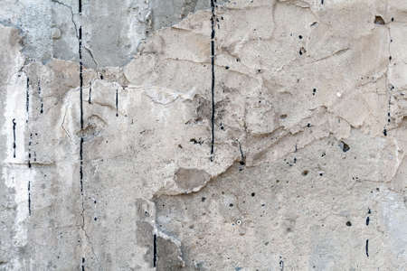 Gray wall covered with an uneven rough layer of plaster with holes, irregularities, cracks and thin traces of flowing black resinの写真素材