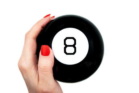 Magic 8 ball of predictions in female hand with red nails isolated on white backgroundの写真素材