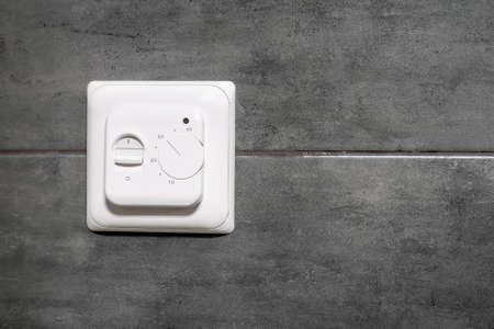 White switch and underfloor heating  on a grey concrete wall in a modern bathroomの写真素材