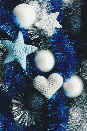 Knitted stars, heart and Christmas balls are on the blue and silver garlandsの写真素材