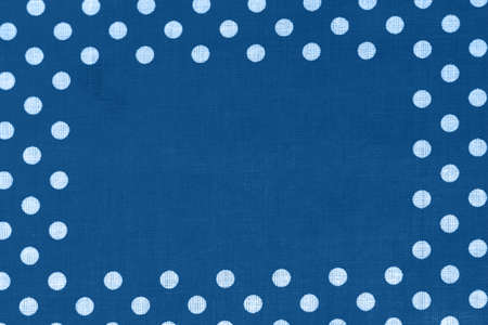 Polka dot on classic blue canvas cotton texture with copy space in the middle. Blue fabric with printed white circles. Bright colored cotton backgroundの写真素材