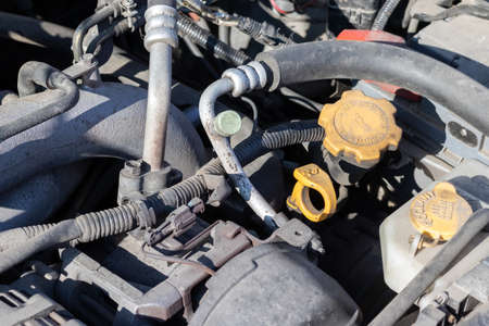 Oil probe, oil cap and antifreeze tank. Dusty details of a flat-four (boxer) car engine compartment under the open hood. Closeup view on a sunny dayの写真素材