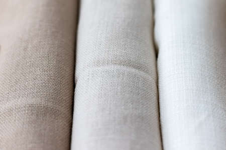 Vertical textural background of three types of natural linen fabric, rolled up. Selective focus. Closeup viewの写真素材