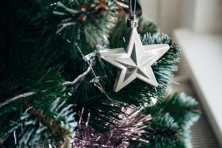 Silver star and pale pink garland on artificial Christmas tree. Selective focus. Holiday card with decorations for the New Year's Eveの写真素材