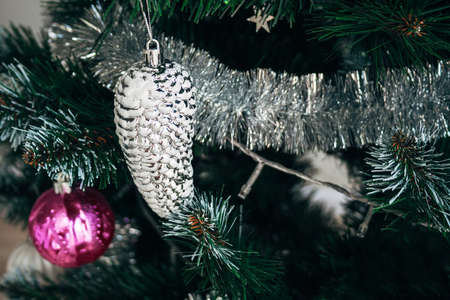 Silver white toy cone and silver garland on artificial Christmas tree. Selective focus. Holiday card with decorations for the New Year's Eveの写真素材