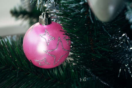 Pink ball on artificial Christmas tree. Selective focus. Holiday card with decorations for the New Year's Eveの写真素材