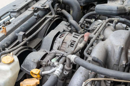 Dusty details of a flat-four (boxer) car engine compartment under the open hood. Closeup side view....