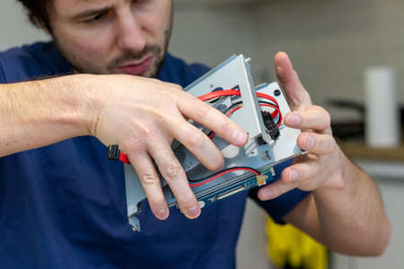 Young man assembles electronic computer components with his own hands. Hobby, technician,...