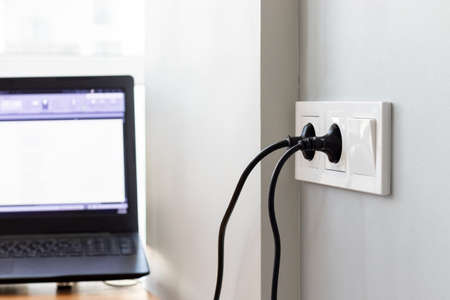 Group of white european electrical outlets with a two black plugs inserted into it and a switch...