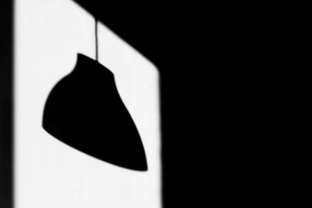 The shadow of the ceiling lamp on a rectangular trail of sunlight on the wall. Black and white photoの写真素材
