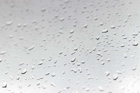 Raindrops on a window glass in rainy cloudy day against a gray sky. Autumn, depressive, rainy weather. Selective focusの写真素材