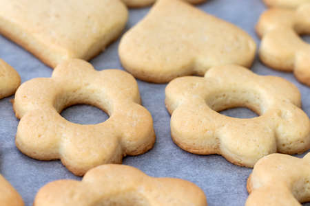 Baked shortbread cookies in the form of flowers and hearts on a baking sheet with parchment paper...