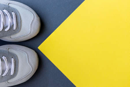 Light gray sports or walking sneakers made of suede and mesh on a gray yellow paper background with copy space. Top view, flat layの写真素材