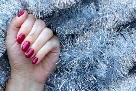 Female hand with a beautiful glossy manicure - burgundy, dark red, cherry color nails on background...