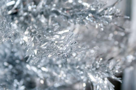 Silver artificial Christmas tree branches background. Selective focus. Closeup view
