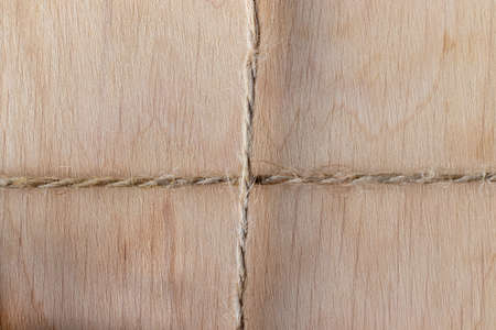 Wooden background drawn by a waxed cord. Light wood texture and rope crosswise in rustic style