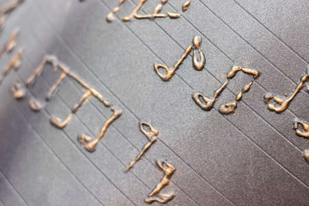 Kyiv, Ukraine - February 29, 2020: Metallic musical notes and a treble clef on a stave on a notebook background. Selective focus. Closeup viewの写真素材