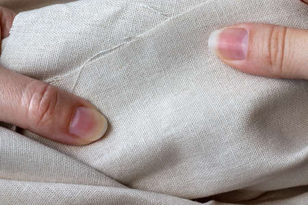 Natural linen fabric in female hands. Rough crumpled burlap. Selective focus. Closeup viewの写真素材
