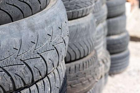 Old used car tires stacked on top of each other near the tire shop. Selective focus. Closeup view....