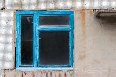 Old dirty window in blue wooden frame in abandoned house