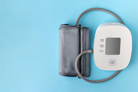 Automatic blood pressure monitor on blue background. Medical electronic tonometer with copy space