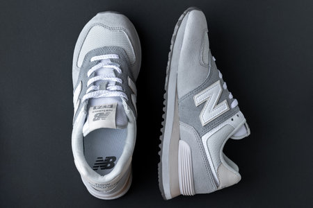 New Balance 574 light gray sneakers on gray background. Suede and mesh walking, casual sport shoes closeup. Illustrative editorial photoのeditorial素材