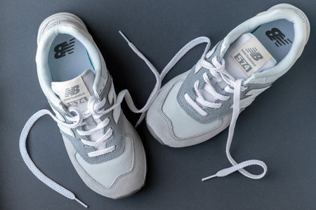 New Balance 574 light gray sneakers on gray background. Suede and mesh walking, casual sport shoes closeup. Illustrative editorial photoのeditorial素材