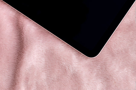 Black tablet with pink border closeup on shaggy fabric. Device screen on textile faux fur blanket backgroundの写真素材