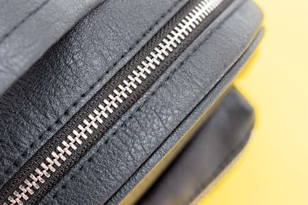 Black eco leather backpack with zipper closeup on yellow background. Selective focusの写真素材