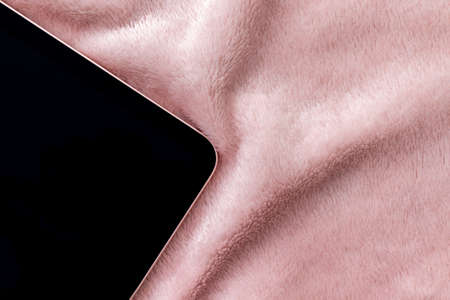 Black tablet with pink border closeup on shaggy fabric. Device screen on textile faux fur blanket backgroundの写真素材