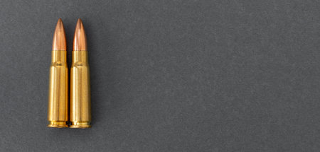 Two bullets on gray paper background. Cartridges 7.62 caliber for assault rifle, closeup banner with copy space.の写真素材