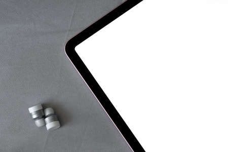 Digital tablet mockup and modern wireless headphones on gray fabric, textile background.
