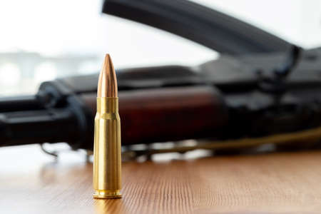 One bullet against blurred assault rifle background. Cartridge 7.62 caliber for ak 47 closeup.の写真素材
