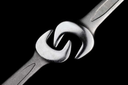 Two steel wrenches isolated on black background closeup. Concept of love, relationship, valentines day. Beautiful photo for a poster in a car workshopの写真素材