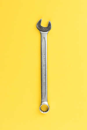Wrench on bright yellow background, steel hand work tool