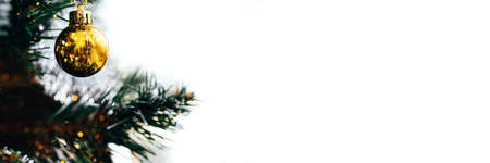 Golden ball on Christmas tree with blurred lights bokeh. Wide panoramic holiday banner with white...