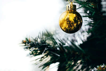 Golden ball on Christmas tree with white copy space. Holiday card with decorations for the New Year's Eveの写真素材