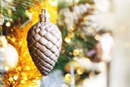 Silver gray toy cone on decorated Christmas tree with blurred lights bokeh. Holiday card with decorations for the New Year's Eve. Selective focusの写真素材