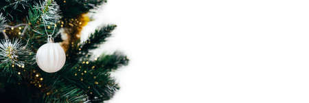White ball on Christmas tree with blurred lights bokeh. Wide panoramic holiday banner with white copy spaceの写真素材