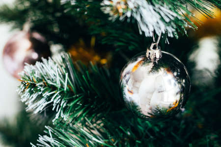 Silver ball on decorated Christmas tree. Selective focus. Holiday card with decorations for the New Year's Eveの写真素材