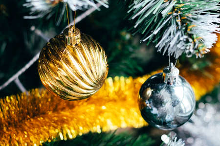Beautiful golden and silver balls on decorated Christmas tree with golden tinsel garland. Selective focus. Holiday card with decorations for the New Years Eveの写真素材